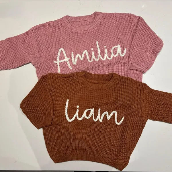 Two baby rompers, one brown and one pink, with embroidered names 'Liam' and 'Amelia' on a white background.